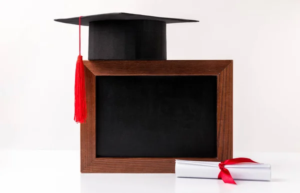 Square academic cup on empty blackboard and diploma isolated on white — Stock Photo