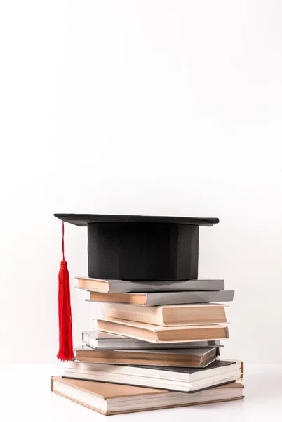 Академічна шапка на стосі різних книг ізольовані на білому — стокове фото