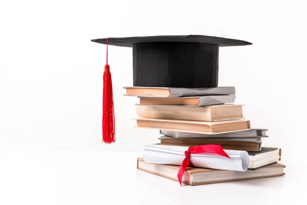 Boné acadêmico na pilha de livros isolados em branco — Stock Photo