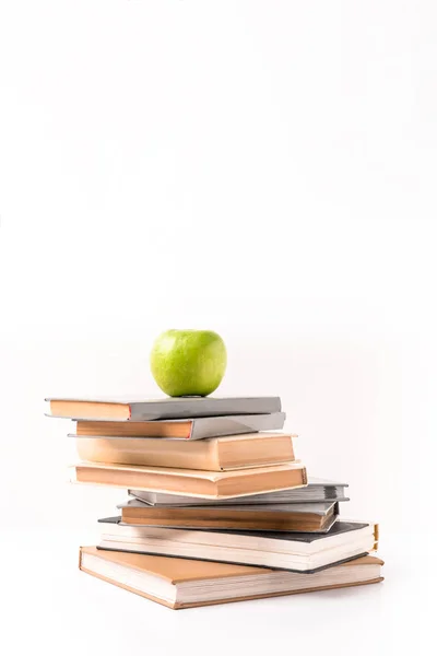 Manzana en un montón de libros aislados en blanco - foto de stock