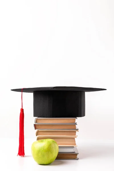 Manzana cerca de pila de libros con tapa académica en la parte superior aislado en blanco - foto de stock