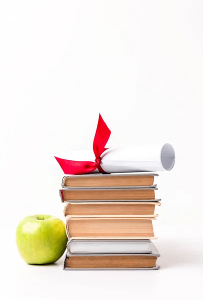 Diploma sobre pila de libros y manzana aislada sobre blanco - foto de stock
