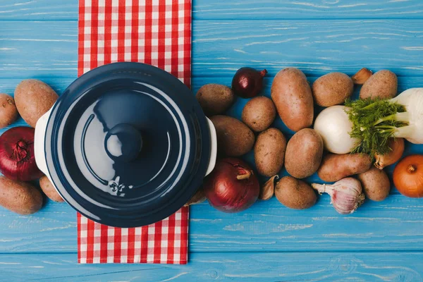 Вид сверху на кастрюли и овощи на голубом столе — стоковое фото
