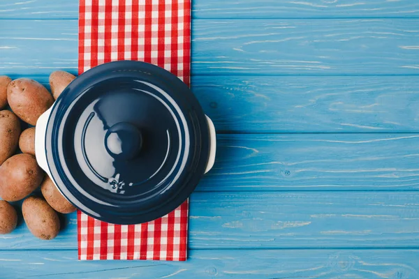 Top view of pan and potatoes on blue table — Stock Photo