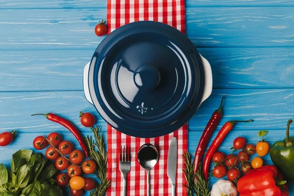 Top view of pan and unprocessed vegetables on blue table — Stock Photo