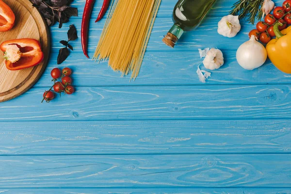 Вид зверху інгредієнтів для приготування макаронних виробів на синій поверхні — стокове фото