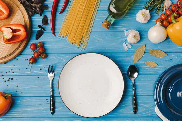 Vista dall'alto del piatto vuoto e degli ingredienti sul tavolo blu — Foto stock