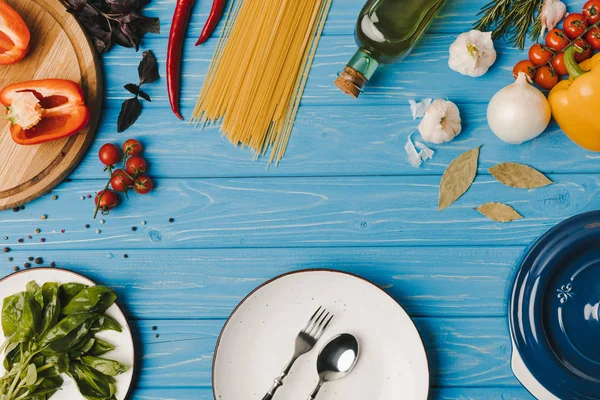 Вид зверху на тарілку з виделкою, ложкою та овочами на дерев'яній поверхні — стокове фото