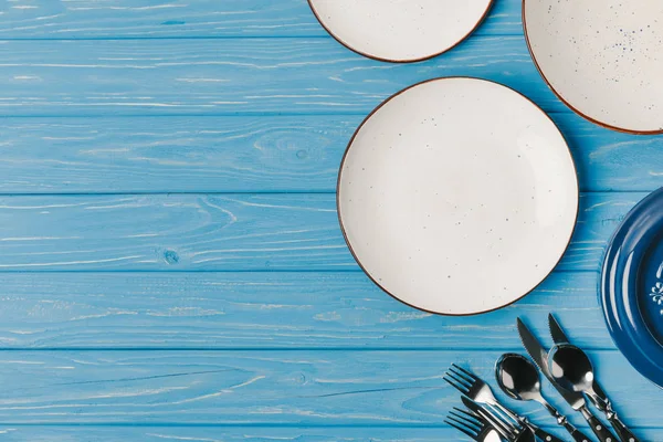 Верхний вид тарелок с посудой на голубой деревянный стол — стоковое фото