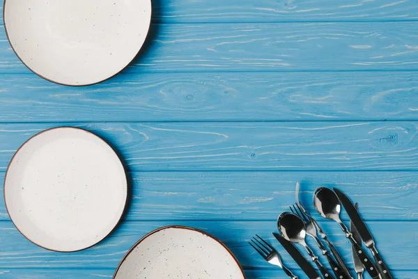 Vista superior de placas com utensílio na mesa azul — Fotografia de Stock