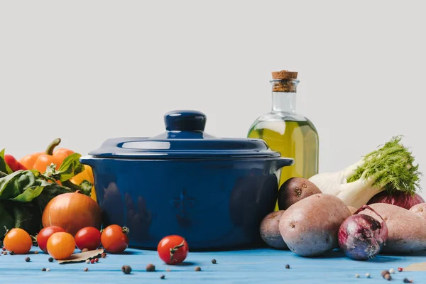 Panela com legumes orgânicos maduros e azeite sobre mesa azul — Fotografia de Stock