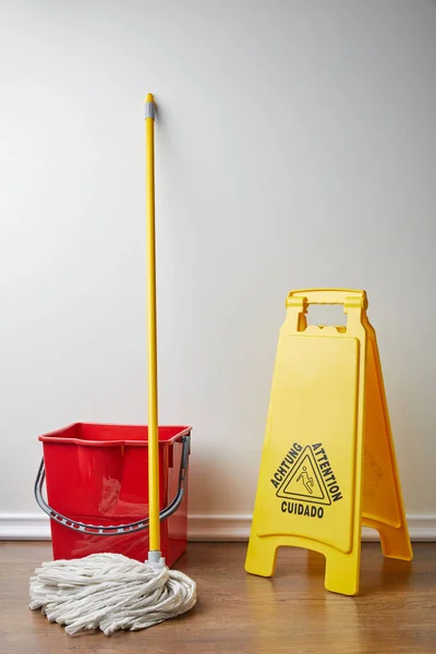 Sinal chão molhado e balde com esfregão para limpeza de mola — Fotografia de Stock