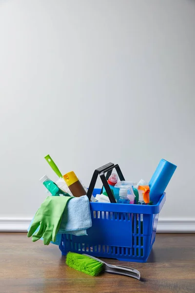 Suprimentos domésticos para limpeza de primavera em cesta azul no chão — Fotografia de Stock