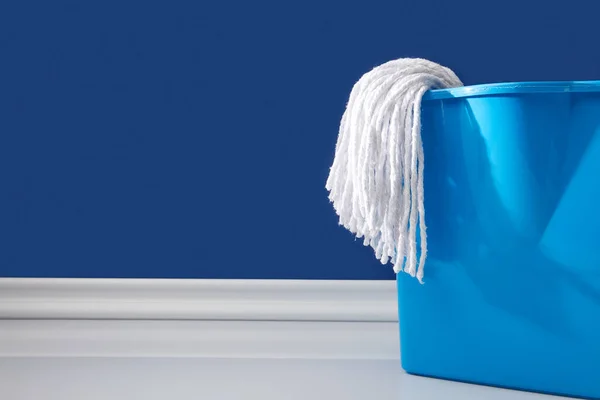 Ганчірка і відро для весняного прибирання на синьому — стокове фото