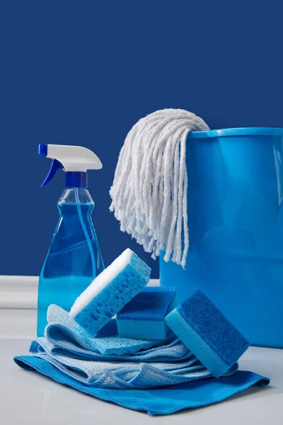 Chiffons, seau et pulvérisation pour le nettoyage du printemps sur bleu — Photo de stock