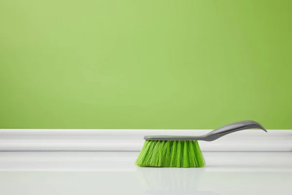 Cepillo verde para la limpieza de primavera en suelo blanco - foto de stock