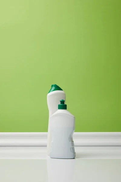 Bottles with domestic supplies for spring cleaning on green — Stock Photo