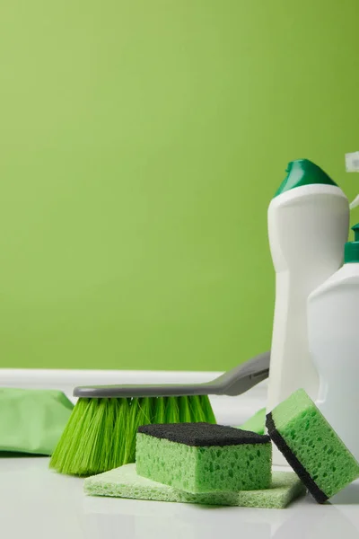 Cepillo verde, esponjas de lavado y botellas de líquidos para la limpieza de primavera - foto de stock