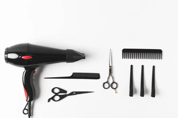 Tendido plano con secador de pelo y herramientas de peluquería, en blanco - foto de stock