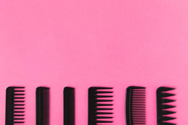 Top view of black combs in row, isolated on pink with copy space — Stock Photo