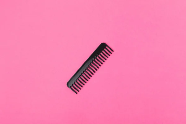 Top view of one black comb, isolated on pink — Stock Photo
