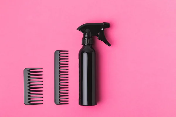 Top view of black combs and spray, isolated on pink — Stock Photo