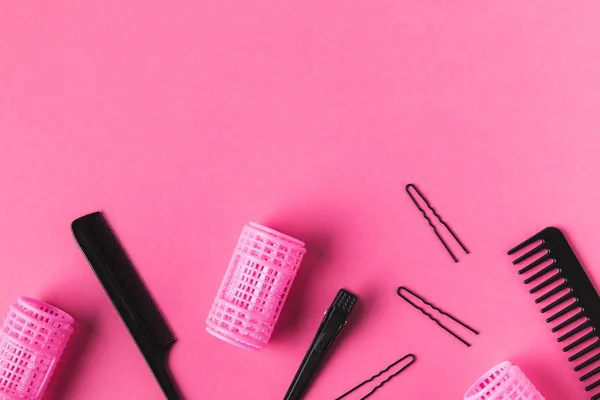 Vue de dessus des bigoudis, peignes et outils de coiffure, sur rose — Photo de stock