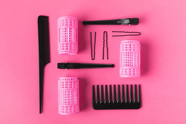 Flache Lage mit Lockenwicklern, Kämmen und Haarspangen, auf rosa — Stockfoto