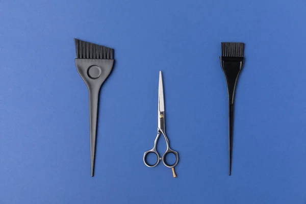 Top view of black brushes and scissors, isolated on blue — Stock Photo