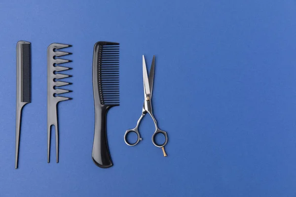 Flat lay with black hairbrushes and scissors, isolated on blue — Stock Photo