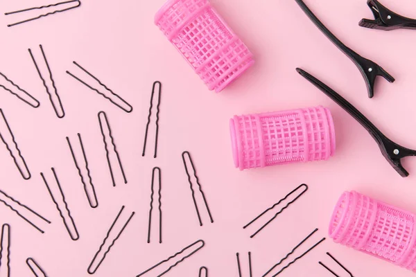 Vue de dessus des épingles à cheveux, des pinces à cheveux et des bigoudis, isolés sur rose clair — Photo de stock