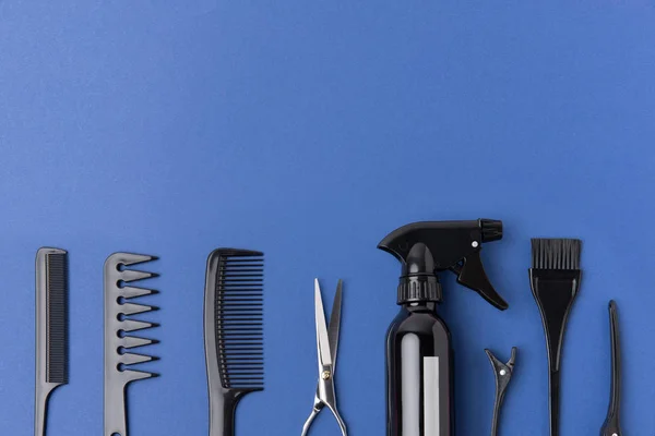 Couché plat avec des outils de coiffure noirs en rangée, isolé sur bleu — Stock Photo