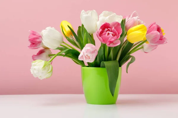 Tender blooming tulips in vase on pink background — Stock Photo