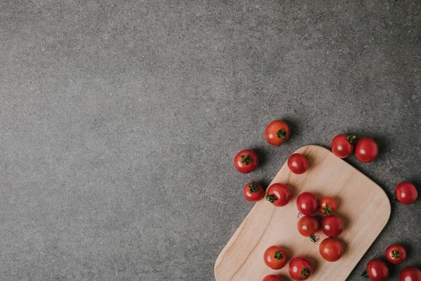Vista superior de tomates maduros frescos sobre tabla de madera en gris - foto de stock