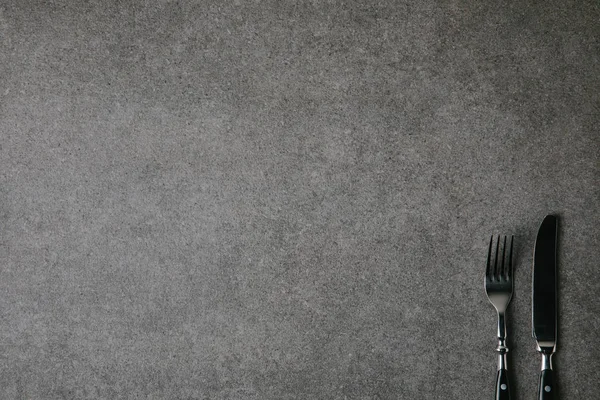 Top view of shiny fork and knife on grey background — Stock Photo