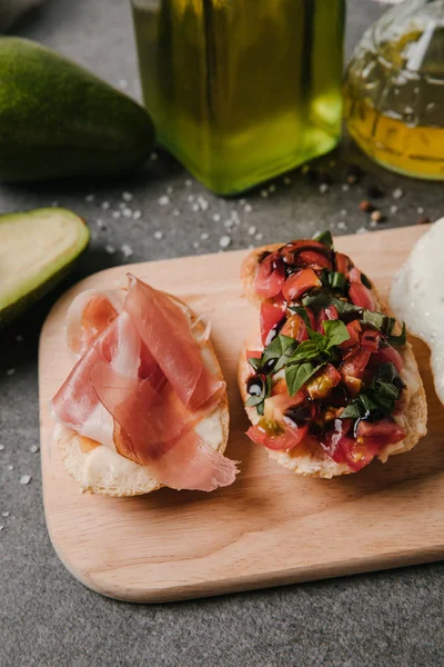 Close-up view of delicious antipasto bruschetta on wooden cutting board — Stock Photo