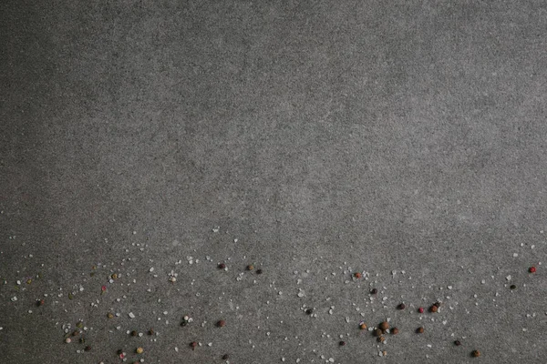 Salt and peppercorns scattered on grey background — Stock Photo