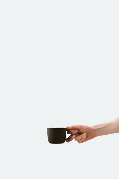 Vista recortada de la mano sosteniendo taza de café de la mañana, aislado en blanco - foto de stock