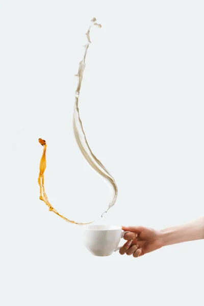 Vista parcial do copo de mão com salpicos de leite e café quente, isolado em branco — Fotografia de Stock