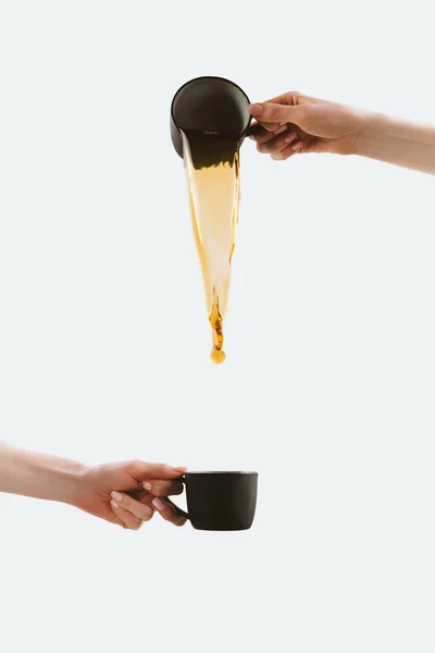 Vista ritagliata delle mani versando caffè da una tazza all'altra, isolato su bianco — Foto stock