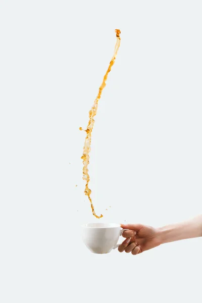 Vista parziale della tazza mano con spruzzi di caffè caldo, isolato su bianco — Foto stock