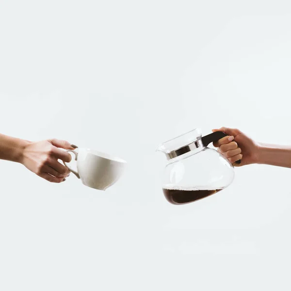 Vista recortada de las manos con taza de café y maceta de vidrio, aislado en blanco - foto de stock