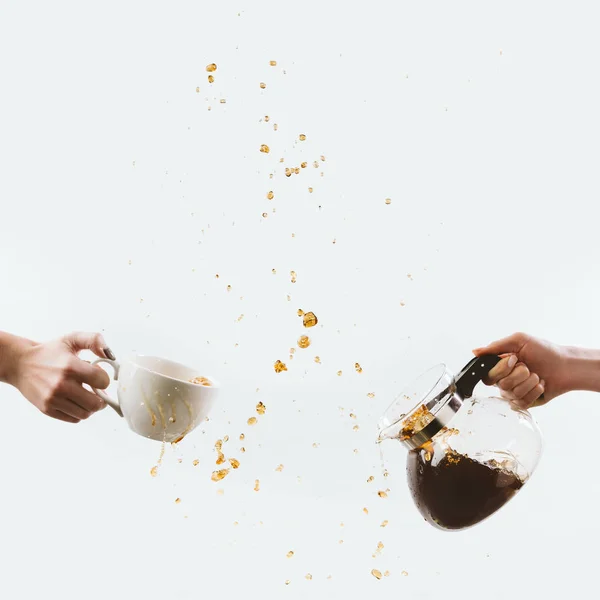 Cropped view of hands with cup and glass pot with drops of coffee, isolated on white — Stock Photo