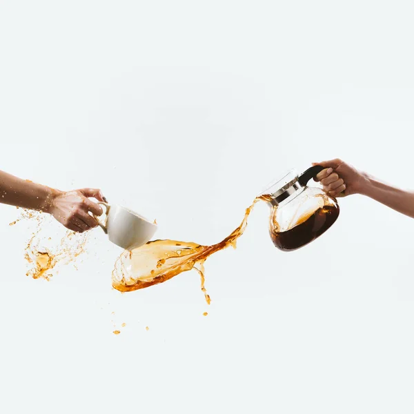 Cropped view of hands splashing morning coffee from cup and glass pot, isolated on white — Stock Photo