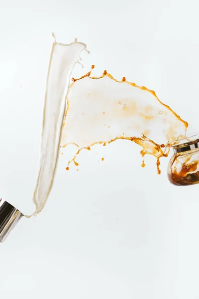 Splashes of milk and coffee from jug and glass pot, isolated on white — Stock Photo