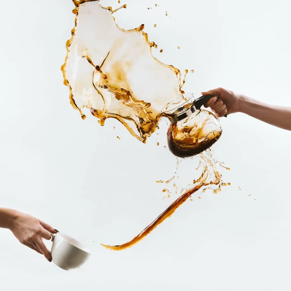 Vista cortada de mãos salpicando café de xícara e panela de vidro, isolado em branco — Fotografia de Stock