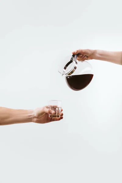 Vista cortada de mãos com panela de café e vidro, isolado em branco — Fotografia de Stock