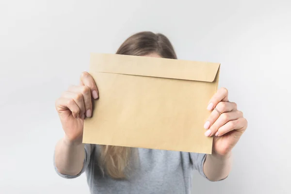 Obscured view of woman showing blank kraft envelope in hands isolated on white — Stock Photo