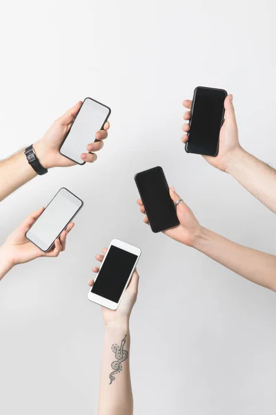 Vista parcial del grupo de personas con smartphones con pantallas en blanco aisladas en blanco - foto de stock