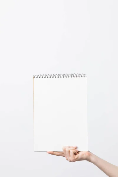 Partial view of woman holding blank sketchbook in hand isolated on white — Stock Photo